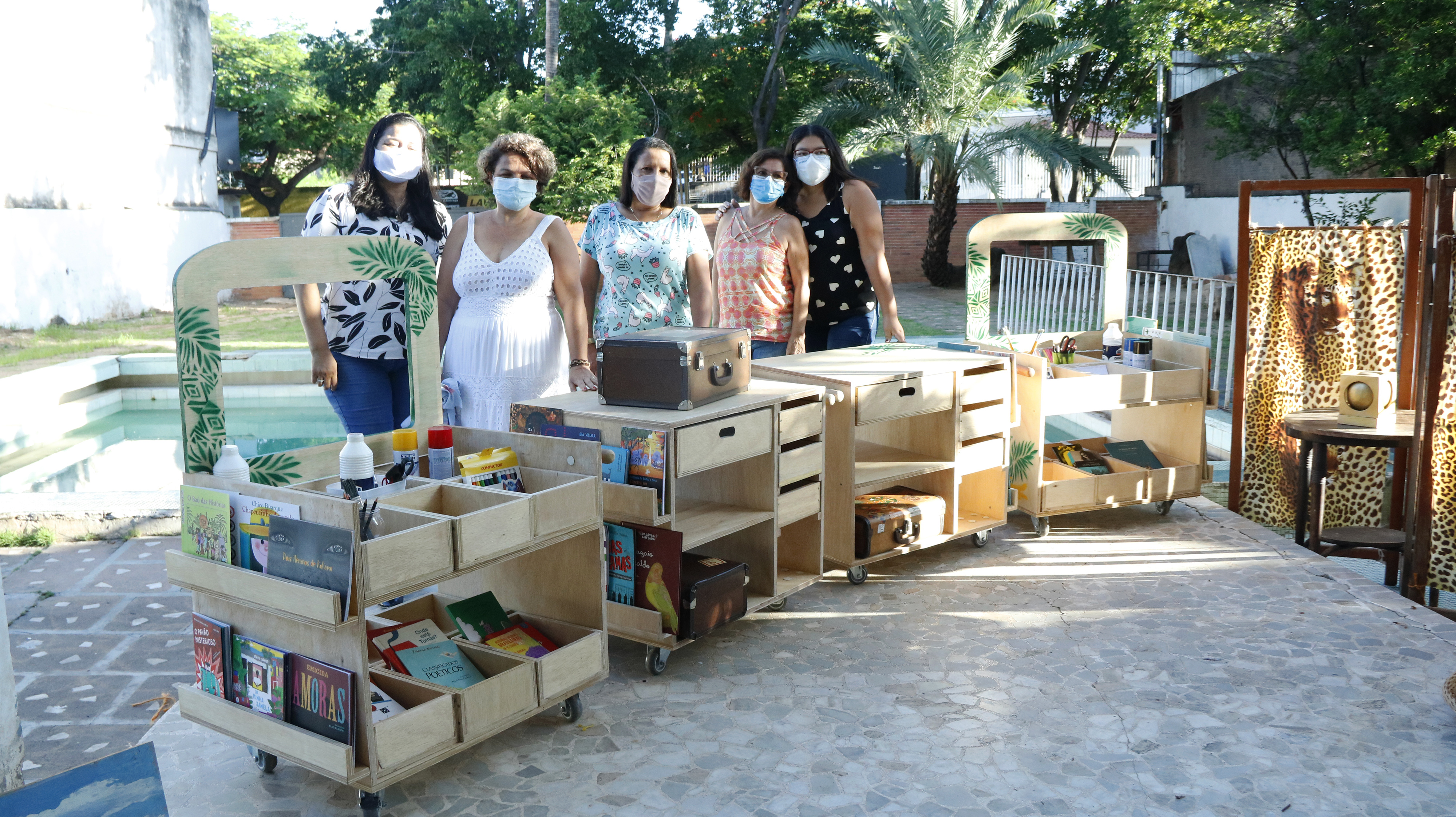 Grupo das construtoras com alguns dos trenzinhos literários feitos de madeira, com rodinhas, gavetas e compartimentos.