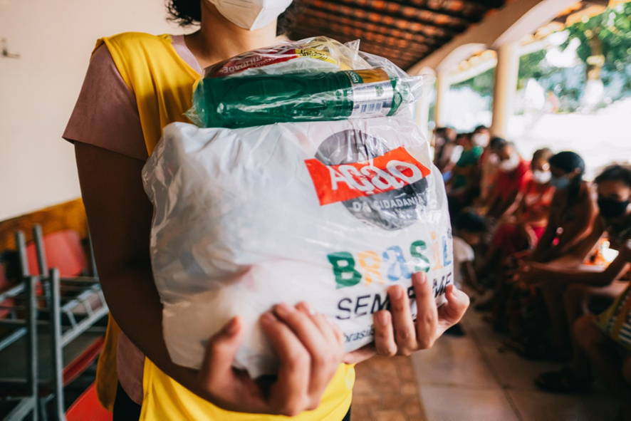 
Image of a person holding a bag of food. Behind her you can see several people sitting down. They are all wearing protective masks.	
